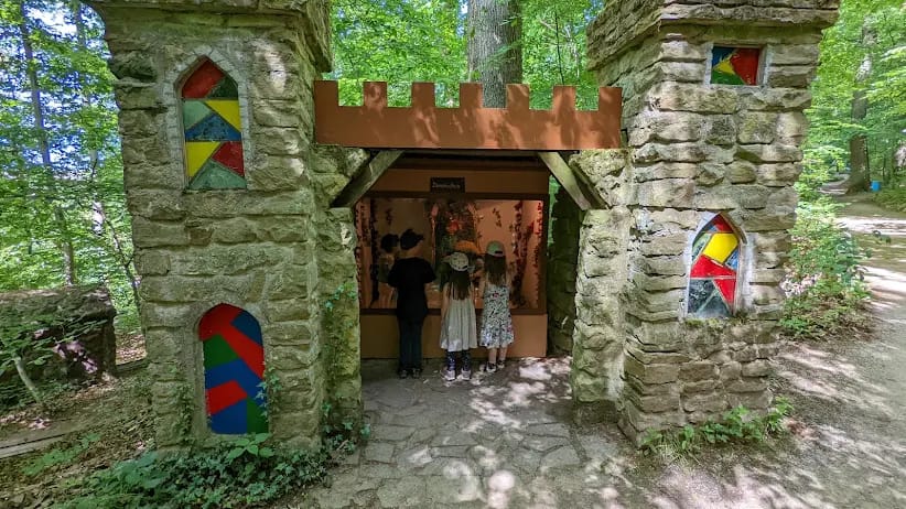 Kinder stehen im Tor einer kleinen Burg aus Naturstein und schauen in eine Märchenszene